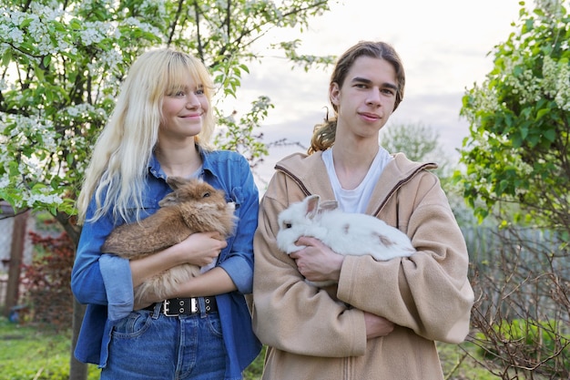 Teenagers with rabbits in their hands pets a couple of decorative rabbits