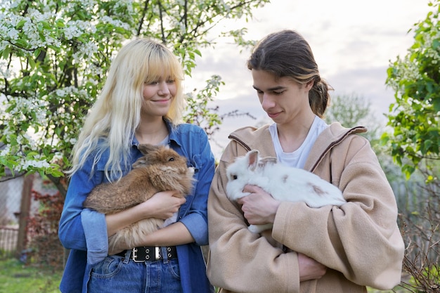 Teenagers with rabbits in their hands pets a couple of decorative rabbits