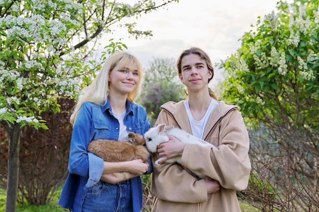 Teenagers with rabbits in their hands pets a couple of decorative rabbits