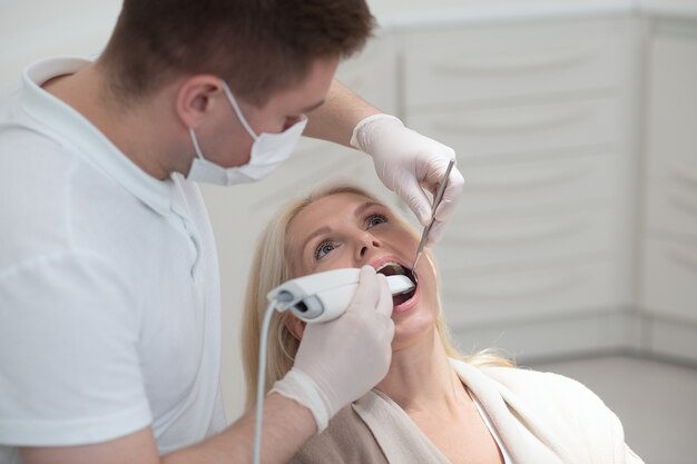 Teeth restoration. Male dentist doing teeth restoration to a female patient