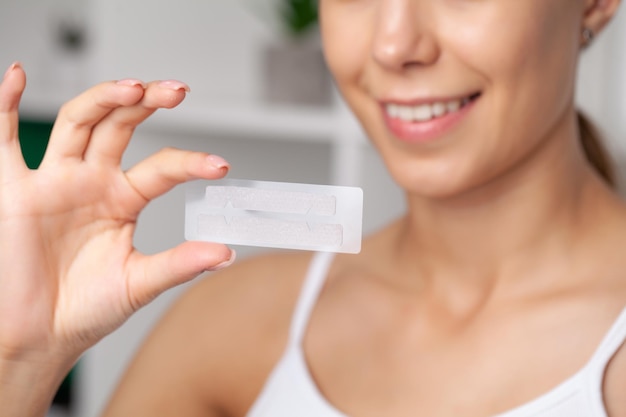 Teeth whitening beautiful smiling woman holding a whitening strip