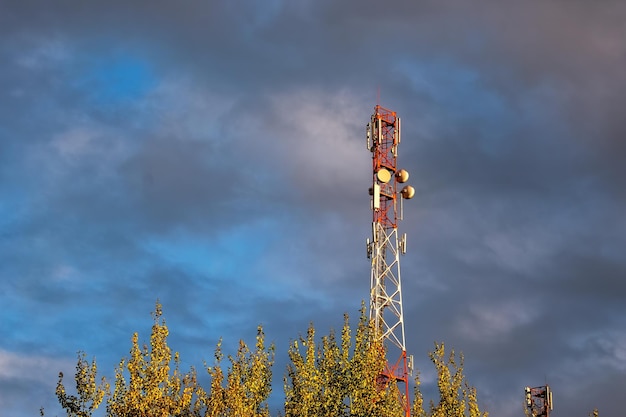 Telecommunication tower with antennas against beautiful colorful blue sky and clouds background