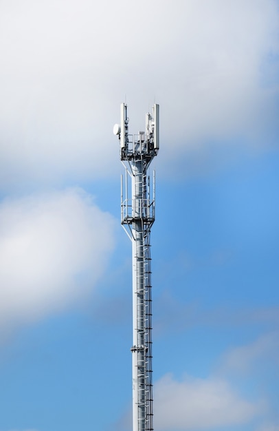 Telecommunication tower with antennas on a background of blue sky and clouds. Smart antennas transmit 4G and 5G cellular signals to consumers.