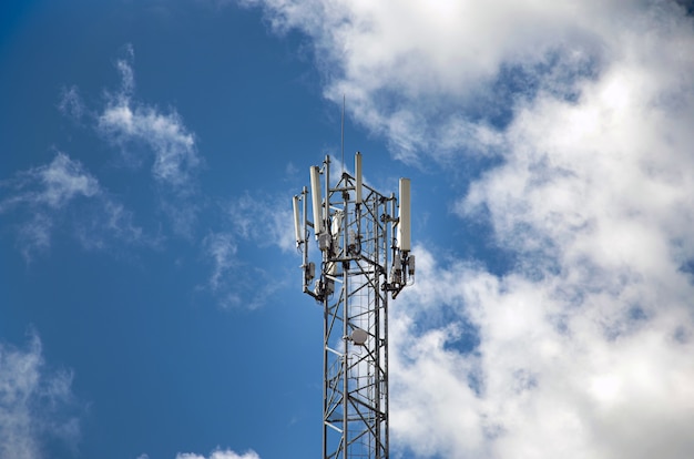 Telecommunications tower with 4G, 5G transmitters. cellular base station with transmitting antennas on a telecommunications tower against the blue sky.