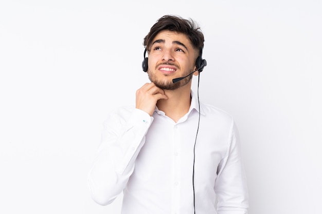 Telemarketer Arabian man working with a headset isolated on white wall thinking an idea