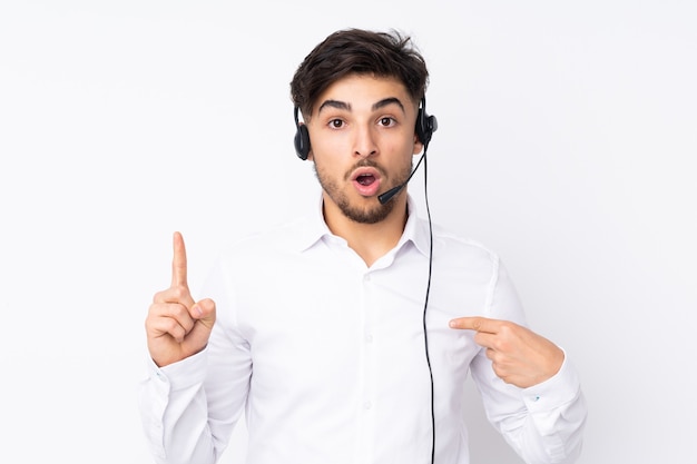 Telemarketer Arabian man working with a headset isolated on white with surprise facial expression