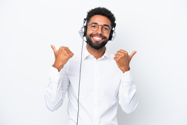 Telemarketer Brazilian man working with a headset isolated on white background with thumbs up gesture and smiling