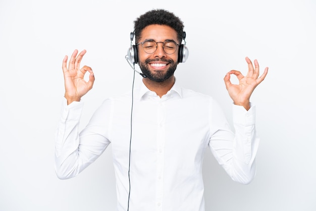 Telemarketer Brazilian man working with a headset isolated on white background in zen pose