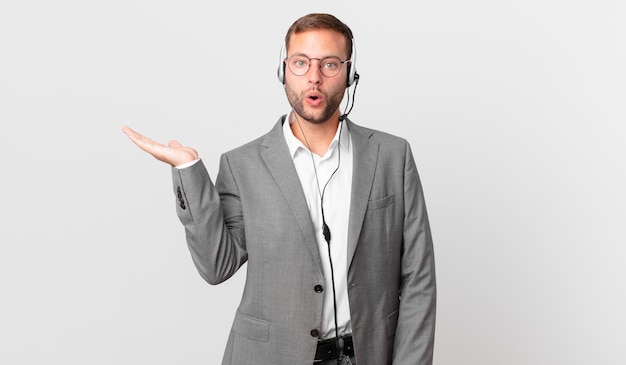 Telemarketer businessman looking surprised and shocked, with jaw dropped holding an object