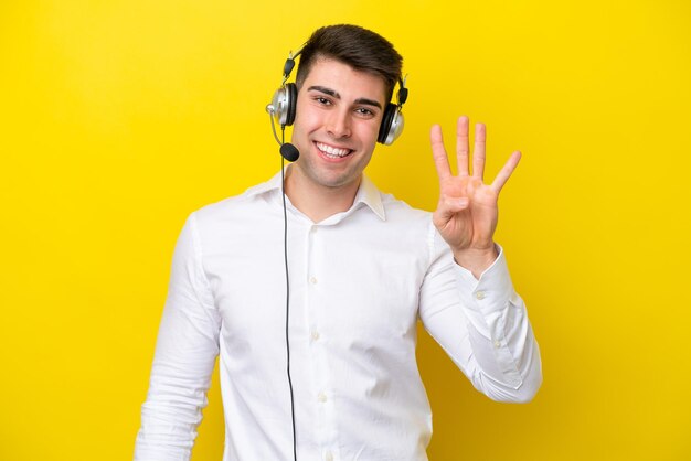 Telemarketer caucasian man working with a headset isolated on yellow background happy and counting four with fingers