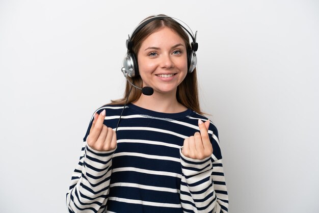 Telemarketer caucasian woman working with a headset isolated on white background making money gesture