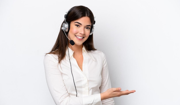 Telemarketer caucasian woman working with a headset isolated on white background presenting an idea while looking smiling towards