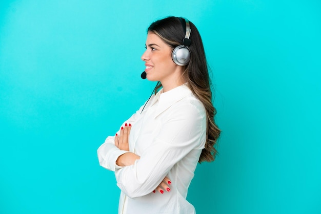 Telemarketer Italian woman working with a headset isolated on blue background in lateral position