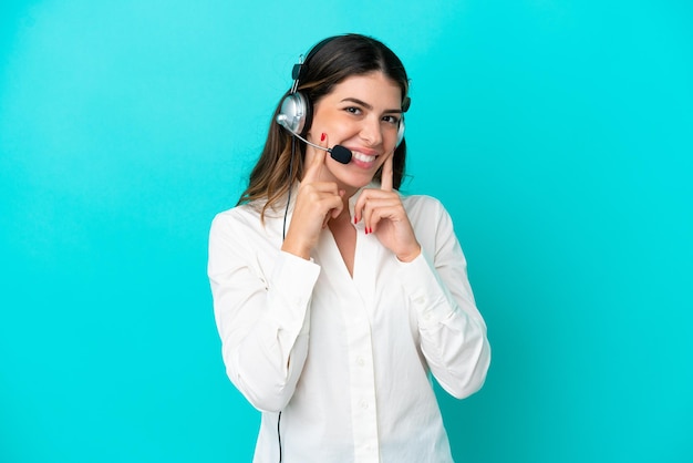 Telemarketer Italian woman working with a headset isolated on blue background smiling with a happy and pleasant expression