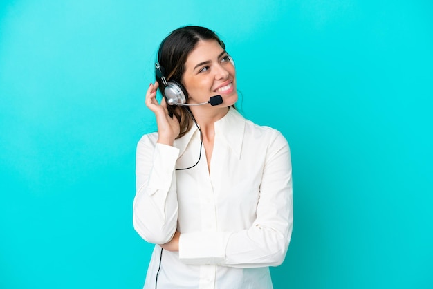 Telemarketer Italian woman working with a headset isolated on blue background thinking an idea