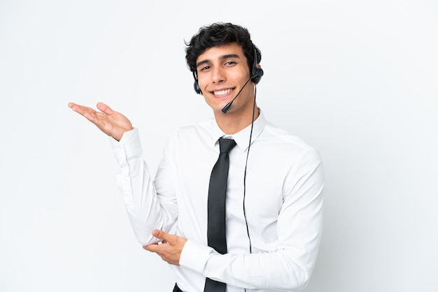 Telemarketer man working with a headset isolated on white background extending hands to the side for inviting to come