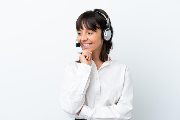 Telemarketer mixed race woman working with a headset isolated on white background looking to the side