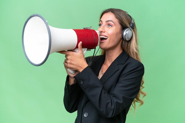 Telemarketer pretty Uruguayan woman working with a headset over isolated background shouting through a megaphone