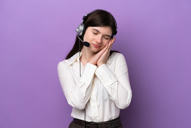 Telemarketer Russian woman working with a headset isolated on purple background making sleep gesture in dorable expression