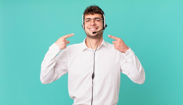 Telemarketer smiling confidently pointing to own broad smile, positive, relaxed, satisfied attitude