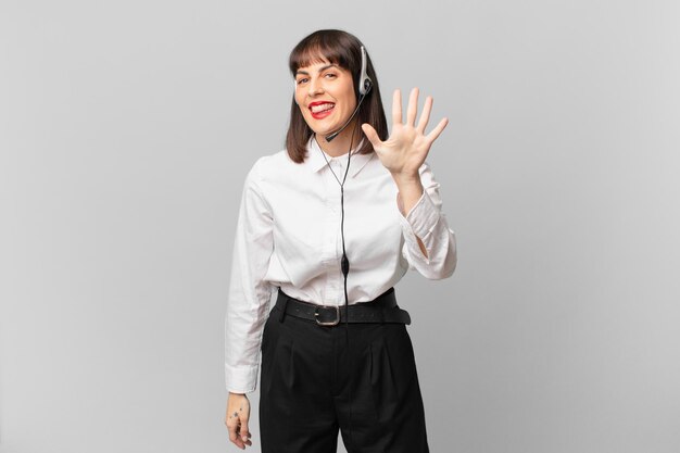 Telemarketer woman smiling and looking friendly, showing number five or fifth with hand forward, counting down