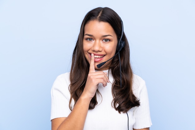 Telemarketer woman working with a headset over isolated wall