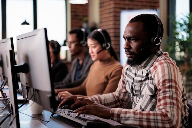 Telemarketing secretary answering client call on headphones at customer care service reception. Young call center operator working on helpline support at helpdesk, giving assistance.