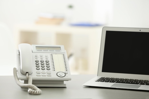 Telephone and laptop on table in office