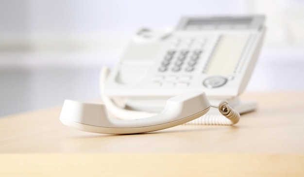 Telephone with picked up receiver on wooden table in office