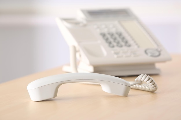 Telephone with picked up receiver on wooden table in office