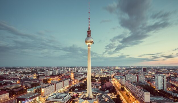 Photo television tower in illuminated city during sunset