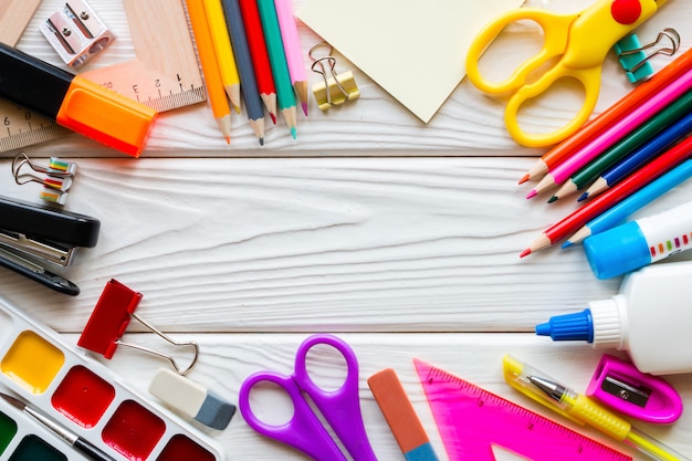 Template of school supplies on a white wooden background