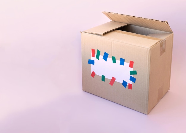 The template for writing on a cardboard box is glued with a white piece of paper with multicolored tape