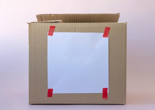 A template for writing on a cardboard box with a white piece of paper glued with red tape