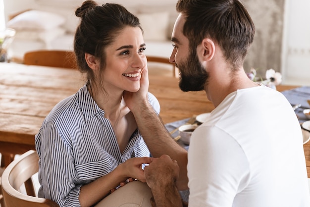 tender brunette couple in love man and woman smiling while hugging together in apartment