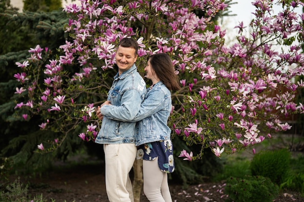 Tender couple in love wear jeans jacket enjoying nice spring day near magnolia blooming tree