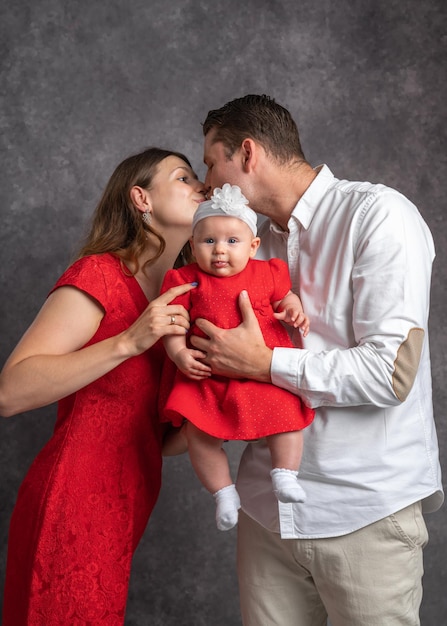 Tender kiss of young parents holding little daughter in their arms