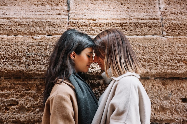 Tender loving women caressing on street