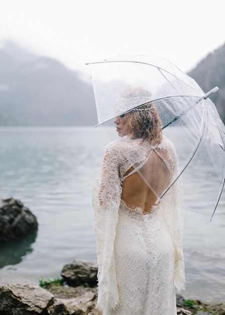 Photo a tender sensual young woman bride in a fashionable wedding dress is standing in the rain in nature