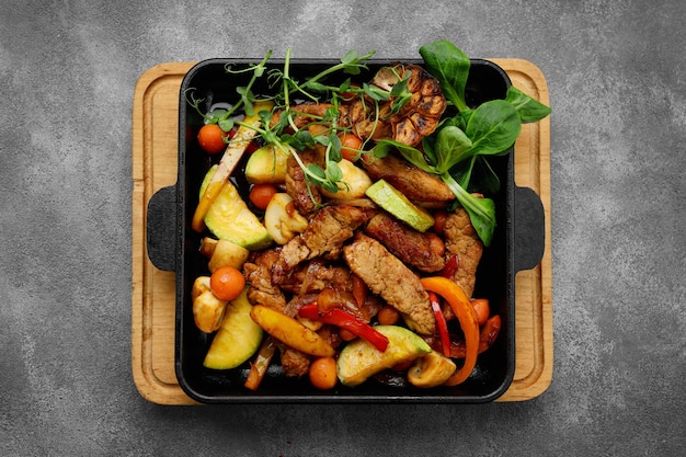 Tender veal with roasted vegetables on black skillet