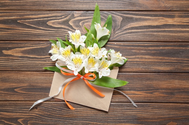 Tender white flowers small orchids in a crafty mail envelope on a wooden background