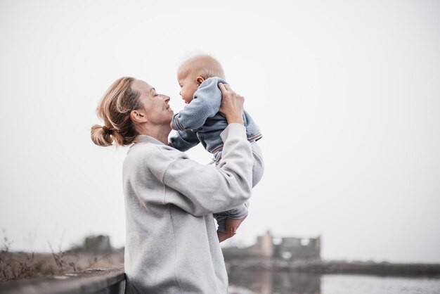 Tender woman caressing her little baby boy infant child outdoors on autumn trip to secovlje salinas