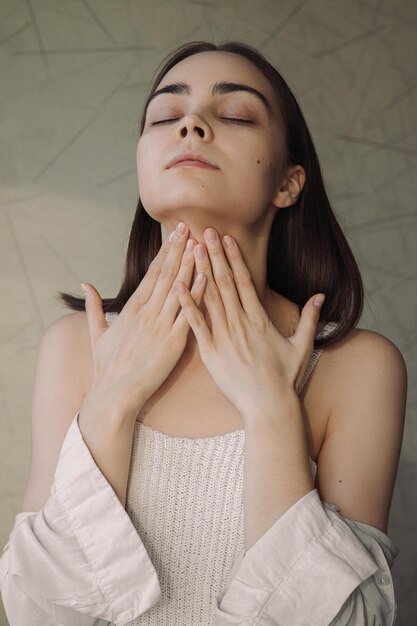 Tender young woman with smooth skin applying cream on neck and doing daily beauty routine