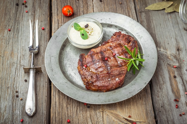 Tenderloin steak on plate with sauce, on a wooden table