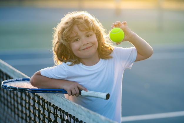 Tennis child kid with tennis racket and tennis ball playing on tennis court