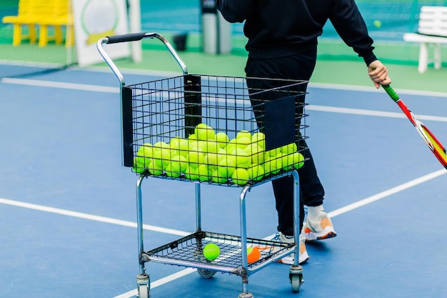 Tennis Coach Conducting Training Session with Tennis Trolley Nearby