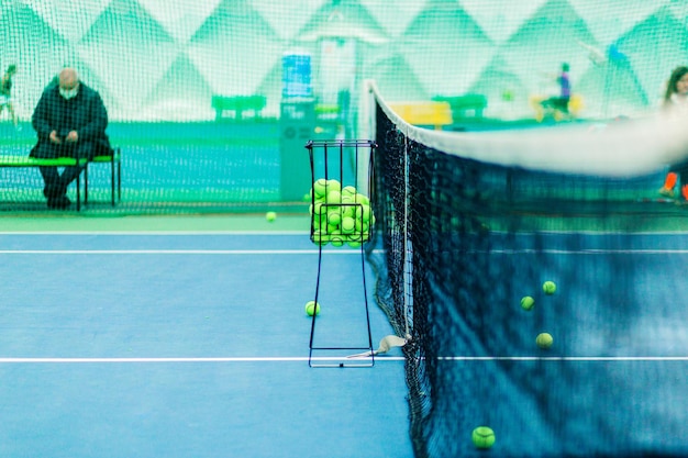 Photo tennis court with basket of balls and net