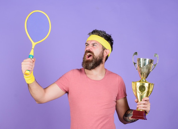 Tennis player win championship Man bearded successful athlete First place Sport achievement Tennis champion Win tennis game Celebrate victory Athletic man hold tennis racket and golden goblet