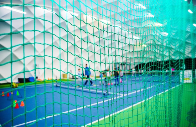 Tennis players practicing on indoor court behind green net