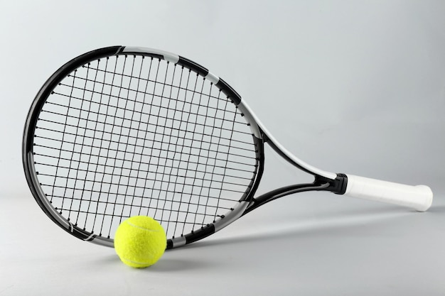 Tennis racket and ball on grey background